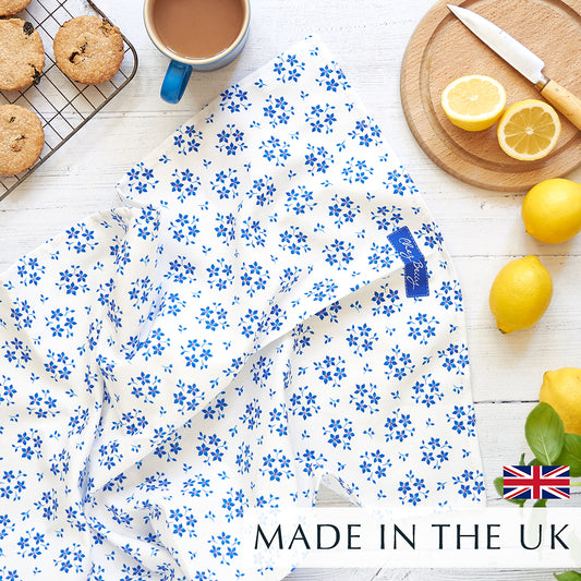 Blue Ditsy Floral Tea Towel on white wooden background and a cup of tea