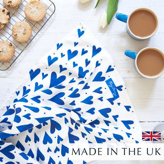 Blue hearts tea towel on a wooden background with 2 cups of tea and homemade biscuits. Made in the U.K