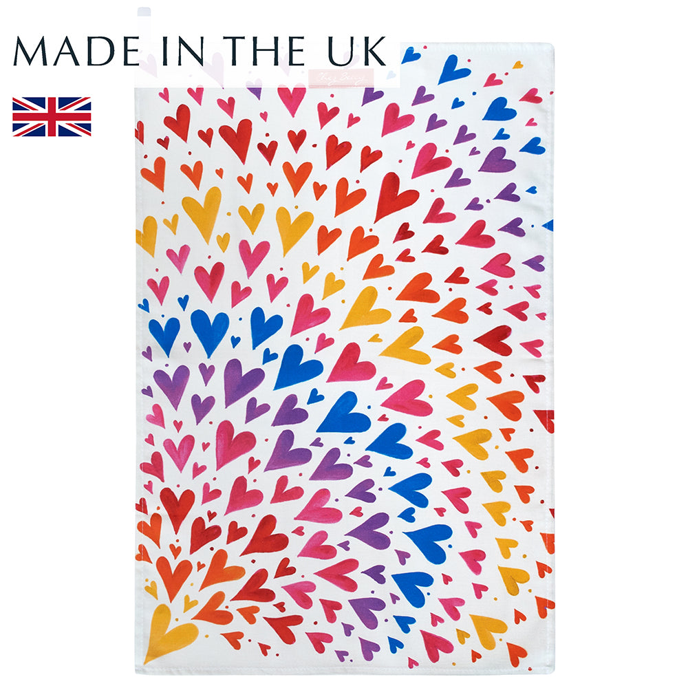 A 100% cotton tea towel featuring a vibrant spray of multicoloured hearts, adding a cheerful touch to any kitchen. Measuring approximately 70cm x 47cm, it's both absorbent and stylish. Designed and made in the UK.