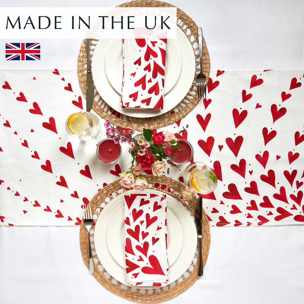 Red Hearts table runner on a white tablecloth with 2 place settings