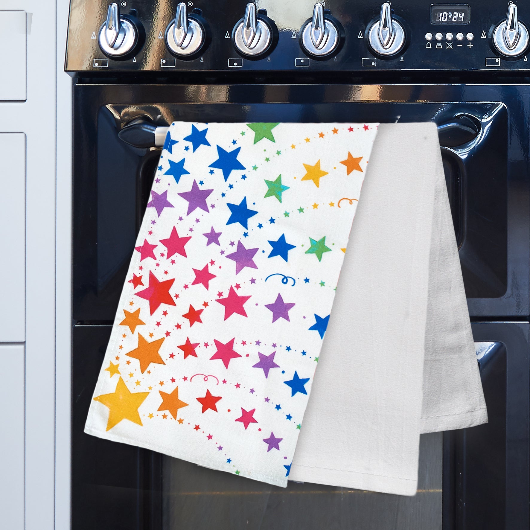 Rainbow stars tea towel and plain white tea towel on a range cooker