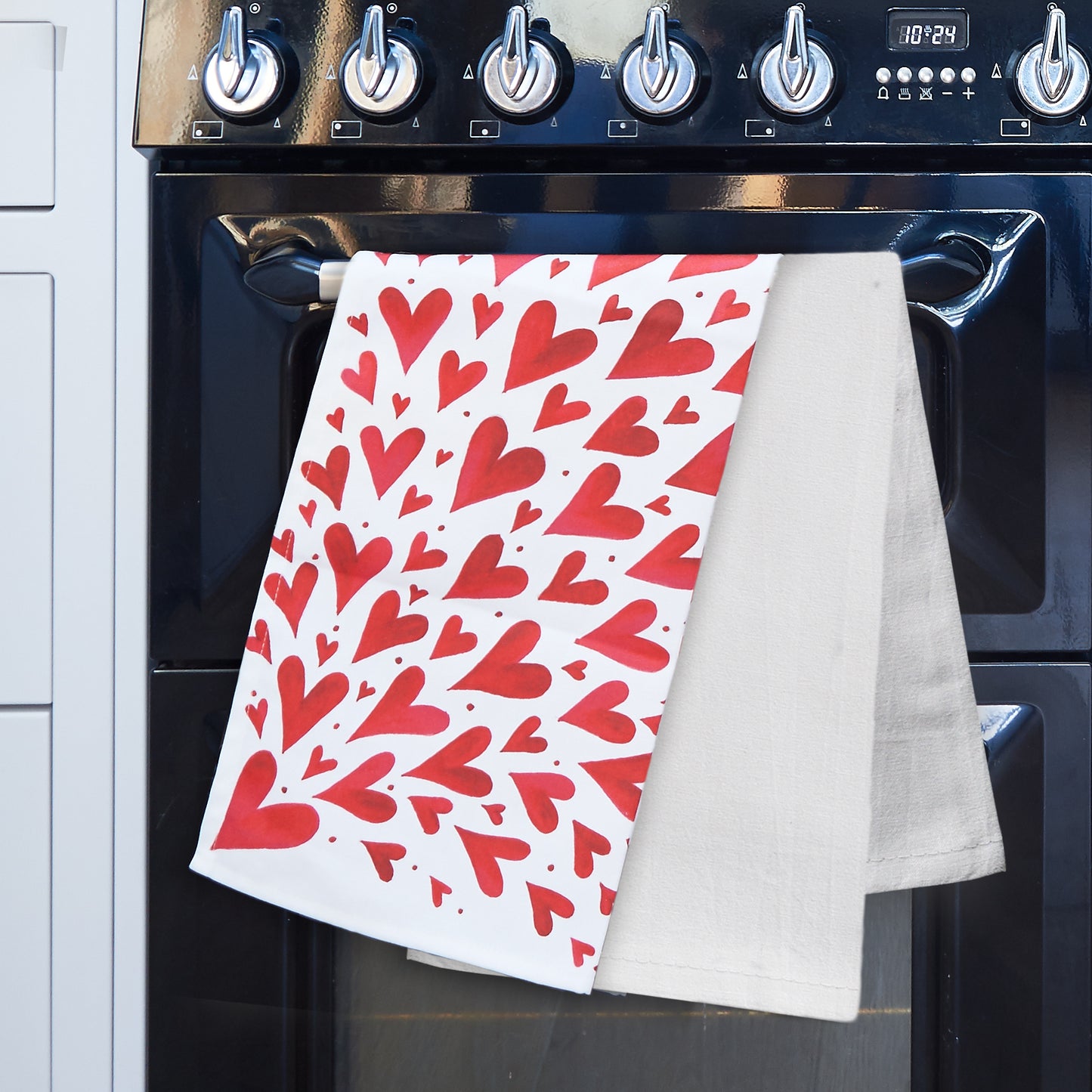 Red hearts tea towel and plain white tea towel on a black range cooker