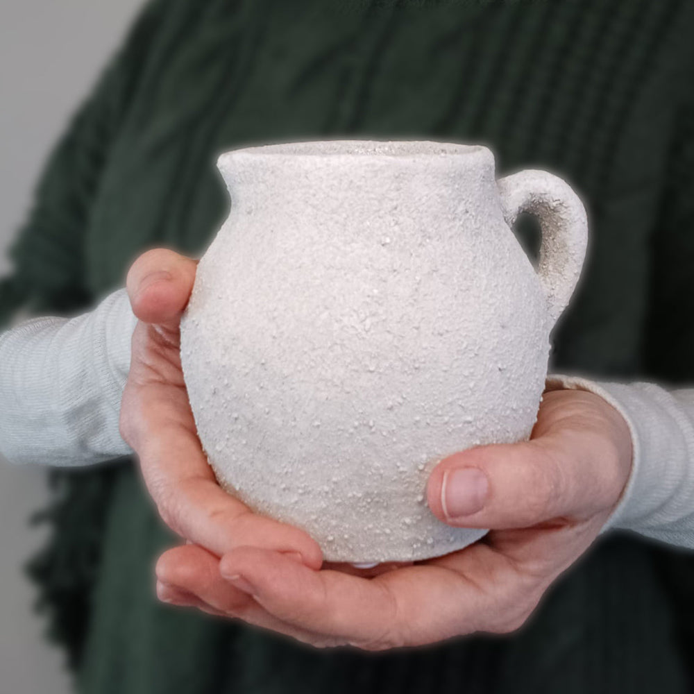 Rustic white Cotswold-style ceramic jug with a textured finish and curved handle. Perfect for displaying fresh flowers, serving drinks, or adding farmhouse charm to any home. A timeless decorative piece for vintage and country-style interiors.