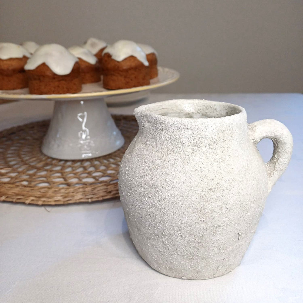 Rustic white Cotswold-style ceramic jug with a textured finish and curved handle. Perfect for displaying fresh flowers, serving drinks, or adding farmhouse charm to any home. A timeless decorative piece for vintage and country-style interiors.