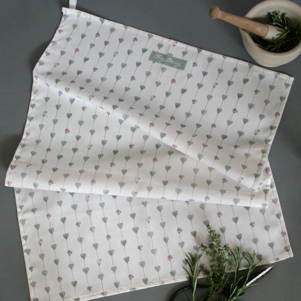 Sage Green Hearts & Roses Tea Towel – A 100% cotton kitchen towel featuring a delicate botanical hearts and roses design in soft sage green, with an ivory hanging loop for convenience.