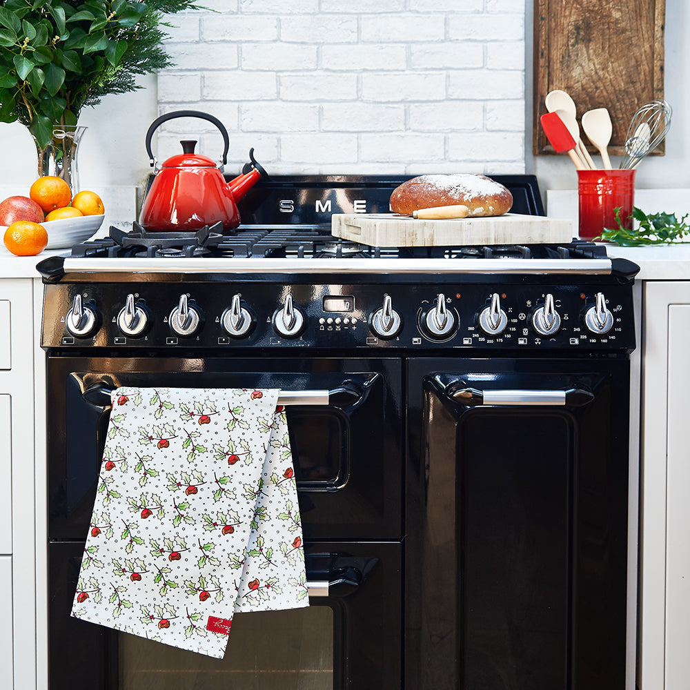Christmas tea towel with robin and holly design on a black range cooker