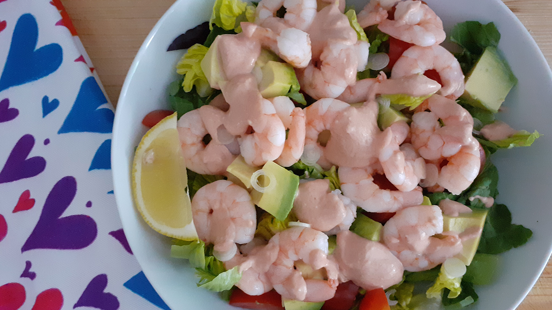 Prawn and avocado salad with a zesty seafood sauce on a board with a colourful hearts tea towel