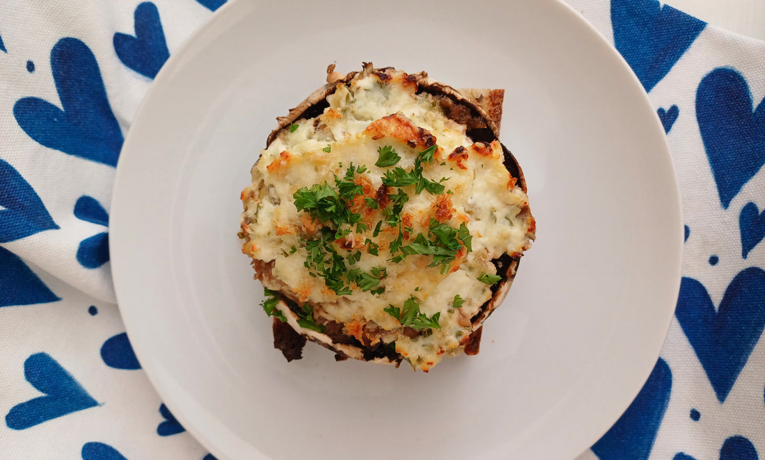 Stuffed mushroom on a white plate with a blue hearts background
