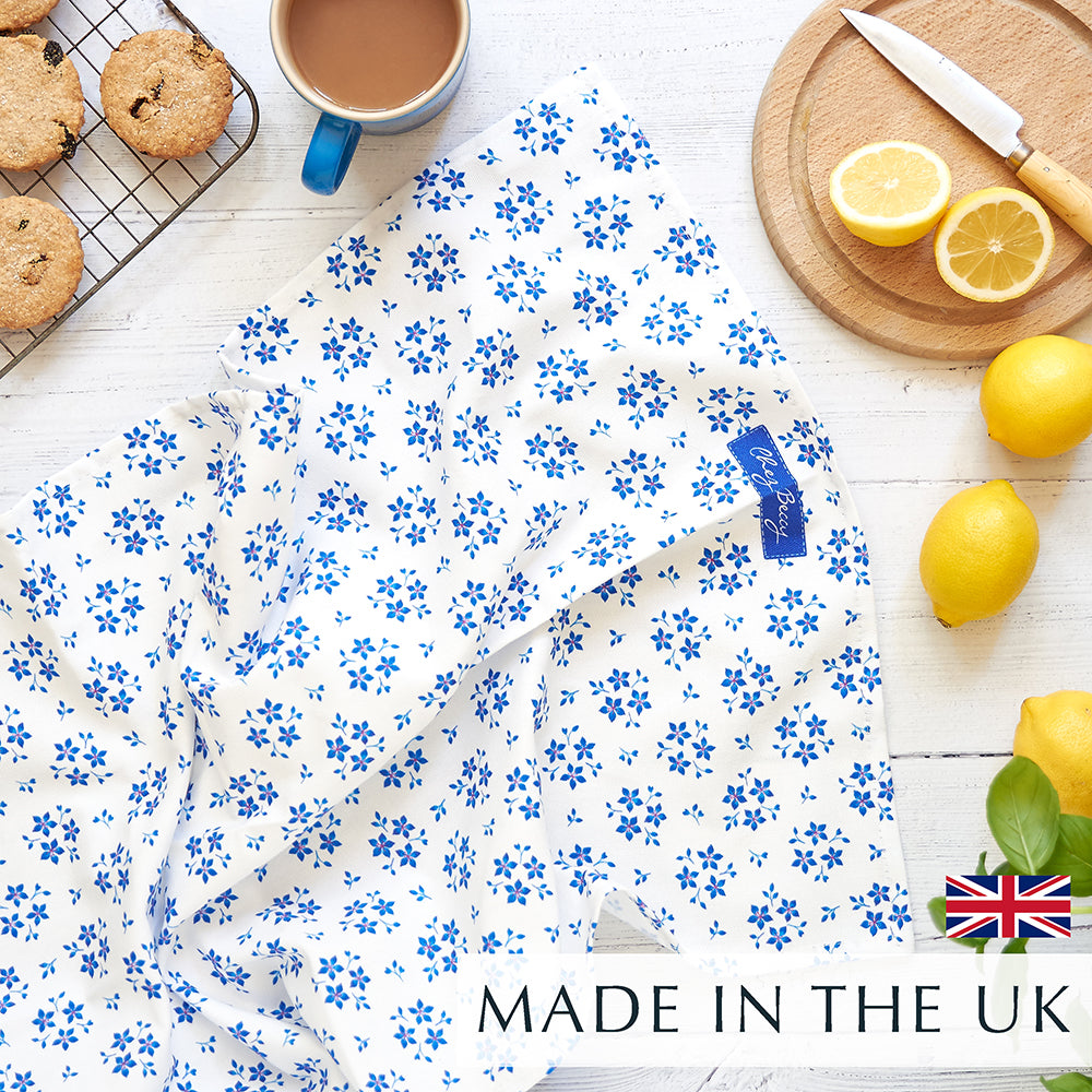 Blue Ditsy Floral Tea Towel on white wooden background and a cup of tea