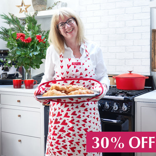 Red hearts apron  holding a plate of croissants with the red heart double oven gloves in a kitchen