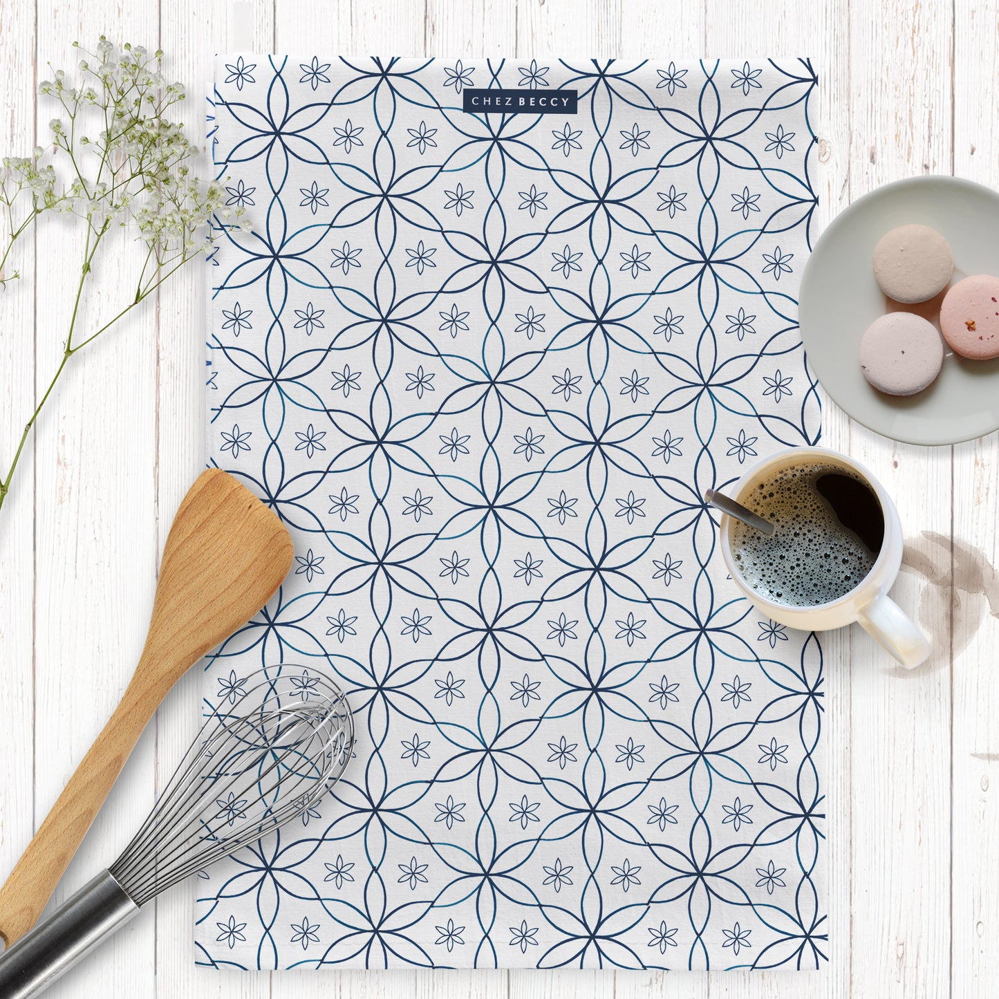 Geometric navy daisy design tea towel on a wooden background with baking props
