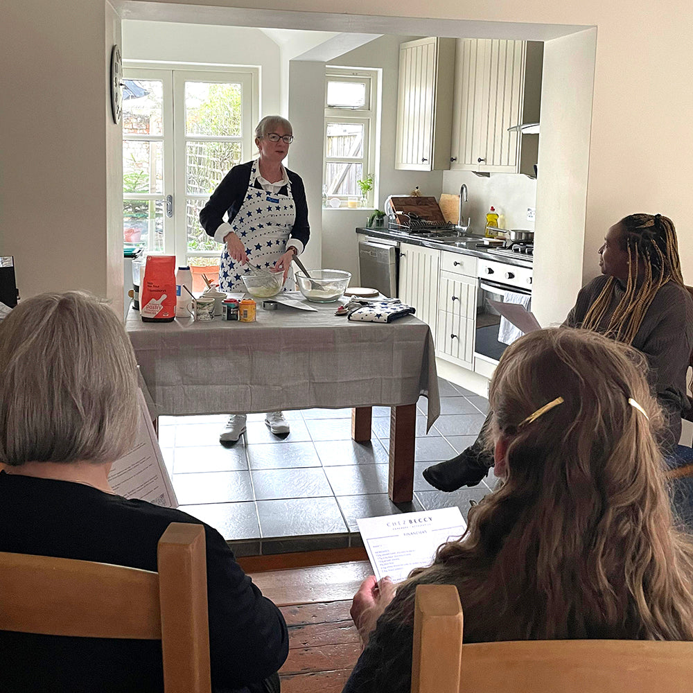 Cook Beccy standing at a table mid baking demonstration
